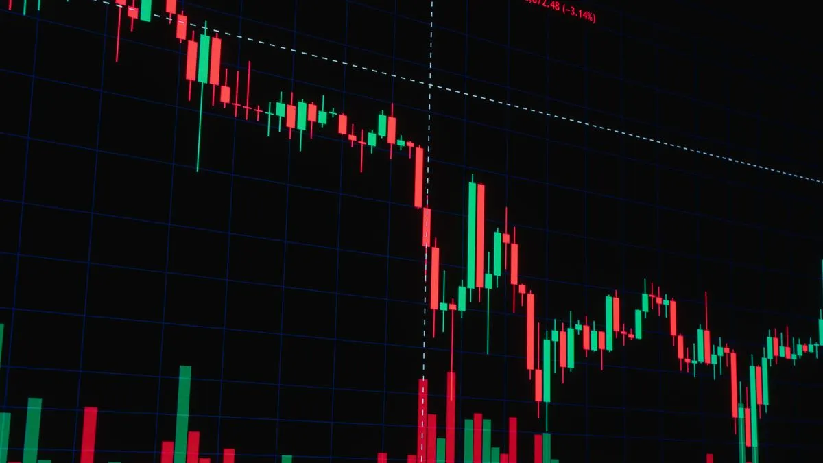 Modèle de Black-Scholes : le prix d'une option expliqué A red and green candlestick chart on a dark trading screen falls steeply past a dashed marker line before levelling out.