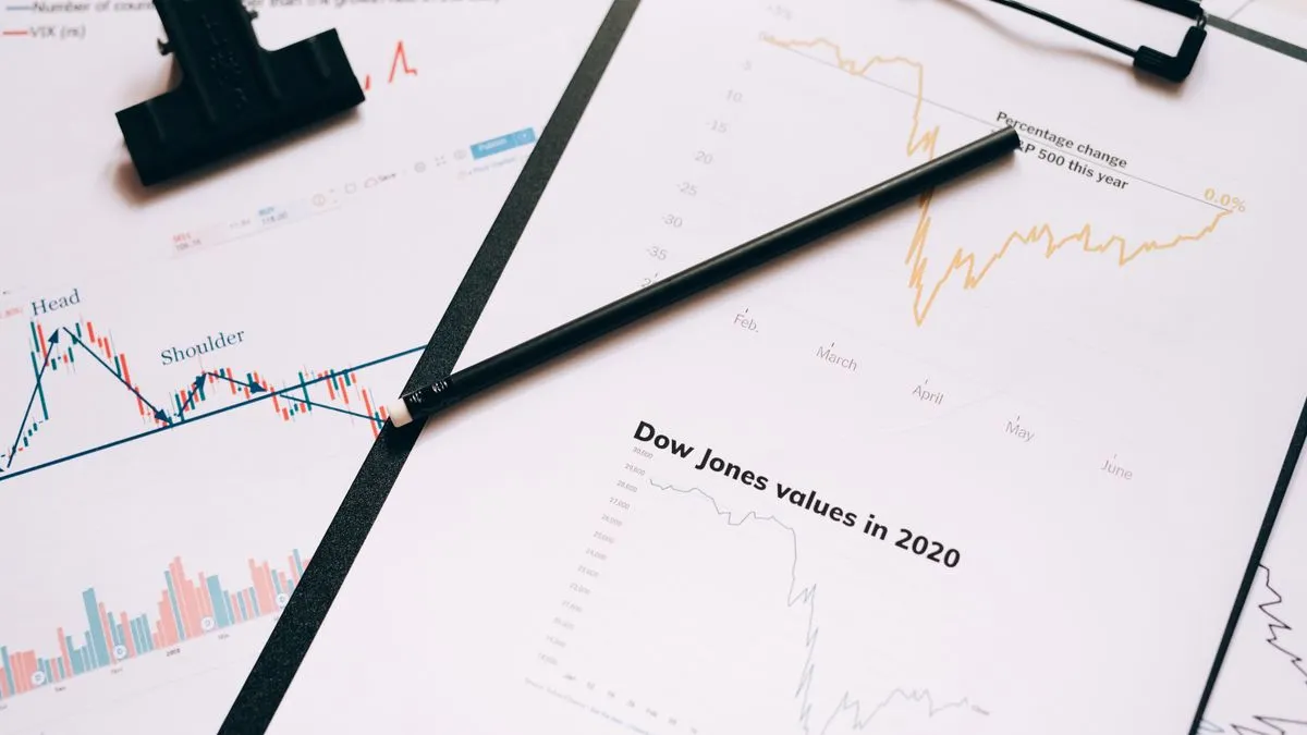 Innerer Wert einer Aktie berechnen: Schritt für Schritt A pen lies across printed stock charts on a clipboard, including a page titled Dow Jones values in 2020.