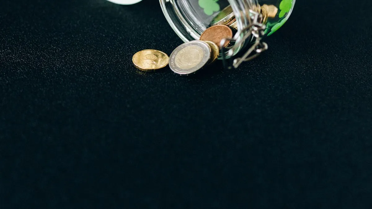 Savings rate: the number that sets your FIRE date A handful of euro coins spills from a tipped glass jar onto a dark surface.