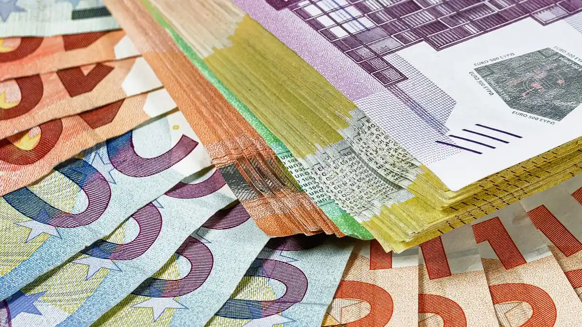 Fanned-out bundles of euro banknotes in several denominations laid on top of each other.