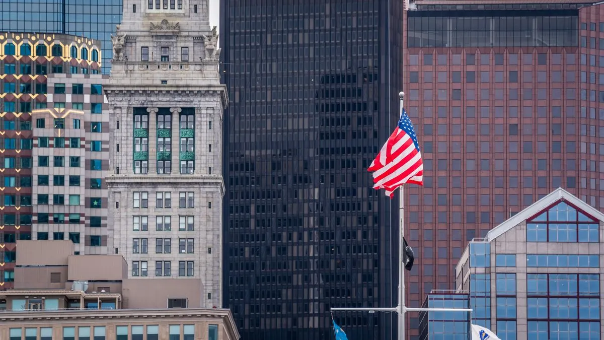 W-8BEN and US Dividend Withholding Tax Explained A US flag flies on a pole in front of downtown Boston, with the Custom House Tower rising among the office blocks.